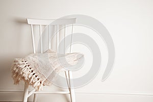 Bedspread or blanket on white vintage chair, minimalistic style. Housekeeping. Copy space.