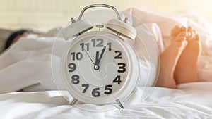 Bedtime sleep with alarm clock at noon or midnight time on bed in bedroom for world lazy day and healthy resting life balance