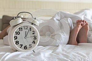 Bedtime sleep with alarm clock at noon or midnight time on bed in bedroom for world lazy day and healthy resting life balance