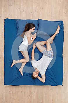 Bedtime. Young couple sleeping head-to-toe on bed top view peaceful