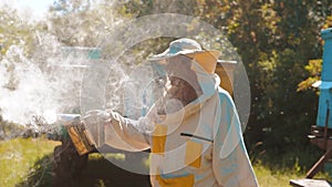 Bee-maker beekeeper man working of a smoke pipe beeper smoker device for repelling evil bees. slow motion video apiary