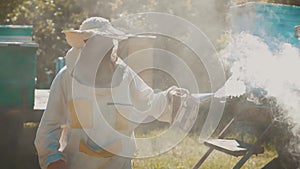 Bee-maker beekeeper man working of a smoke pipe beeper smoker device for repelling evil bees. slow motion video apiary