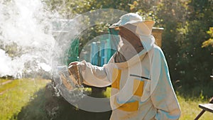 Bee-maker beekeeper man working of a smoke pipe beeper smoker device for repelling evil bees. slow motion video apiary