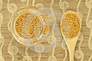 Bee pollen in glass pot and wooden spoon