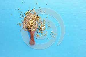 Bee pollen in a wooden spoon healthy food supplements. blue table background. ball or pellet of field-gathered flower