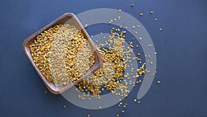 Bee pollen in a wooden spoon healthy food supplements. Close up on a black background. Top view, flat lay. copy space