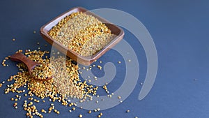 Bee pollen in a wooden spoon healthy food supplements. dark table background. ball or pellet of field-gathered flower