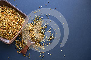 Bee pollen in a wooden spoon healthy food supplements. dark table background. ball or pellet of field-gathered flower