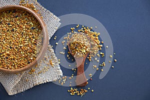 Bee pollen in a wooden spoon healthy food supplements. dark wooden table background. ball or pellet of field-gathered