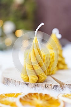 Bee wax candles on a wooden pad, Christmas lights in the background