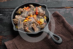 Beef bourguignon stew with vegetables, in cast iron frying pan, on old dark  wooden table