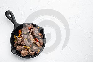 Beef bourguignon stew with vegetables, in cast iron frying pan, on white stone  surface, top view flat lay, with copy space for