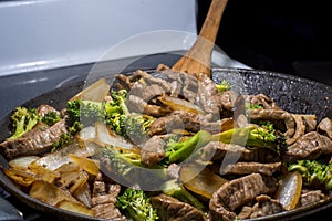 Beef broccoli and onion stirfry steaming in pan photo