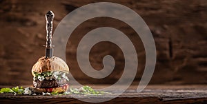 Beef burger with arugula, blue cheese and cranberry saucen with a vintage knife stabbed from the top