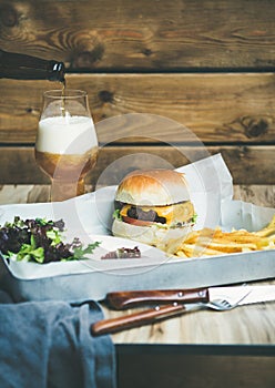 Beef burger, french fries, salad and glass of beer