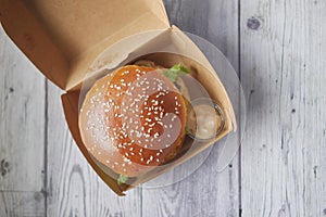 beef burger and french fries in a takeaway paper box on table