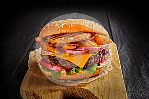 Beef burger with melted cheese and bacon on wooden background