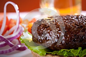 Beef burger with onion and beer on background