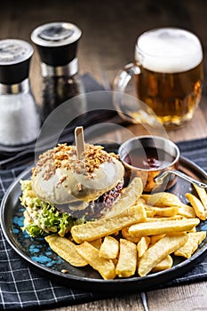 Beef burger topped with cheese with fries and draft beer on a pub or restaurant plate
