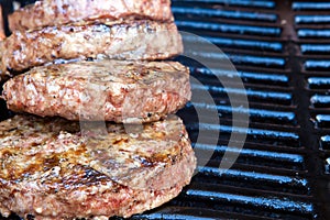 Beef burgers begin to cook on the gas barbecue