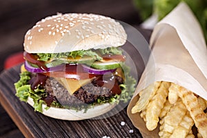 Beef burgers on a wooden board with chips and aromatic spices.