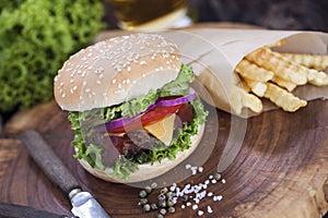 Beef burgers on a wooden board with chips and aromatic spices.