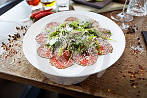 Beef carpaccio. Borettane onion, sun-dried tomato, truffle dressing, arugula salad, parmesan cheese. Italian traditional