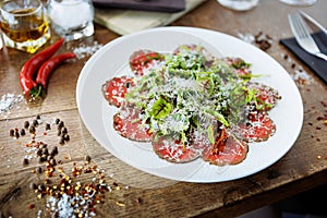 Beef carpaccio. Borettane onion, sun-dried tomato, truffle dressing, arugula salad, parmesan cheese. Italian traditional