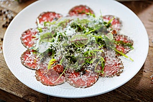 Beef carpaccio. Borettane onion, sun-dried tomato, truffle dressing, arugula salad, parmesan cheese. Italian traditional