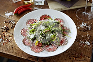 Beef carpaccio. Borettane onion, sun-dried tomato, truffle dressing, arugula salad, parmesan cheese. Italian traditional