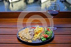 beef chop steak with salad , fried potatoes and mustard sauce in dish.