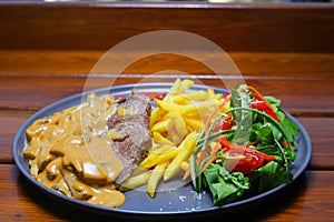 beef chop steak with salad , fried potatoes and mustard sauce in dish.