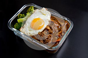 Beef curry rice in glass lunch box on black wooden dining table  Onsen tamago, Potato, enoki mushroom, onion, broccoli, Japanese