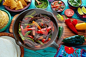 Beef fajitas in a pan sauces chili and sides Mexican
