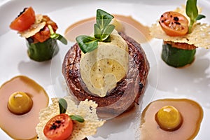 Beef filet dinner entree with garnish and brown sauce displayed on a white dinner plate. Horizontal shot.