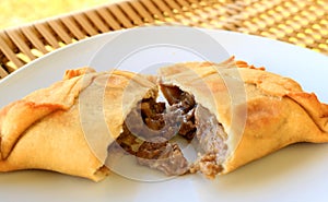 Beef filled Empanada or Empanada de Pino, delicious Chilean baked pasty served on white plate