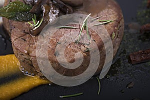 Beef fillet with mushrooms,sundried tomatoes and vegetable puree on a slate plate 11close up shot