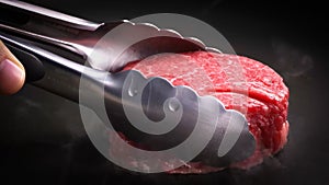 Beef fillet is put into the pan with a steel pliers.