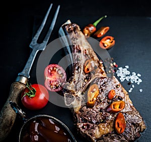 Beef grilled steak served with tomatoes, chili pepper and sauce