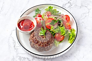 Beef hamburger with lettuce tomato salad on white plate, top view