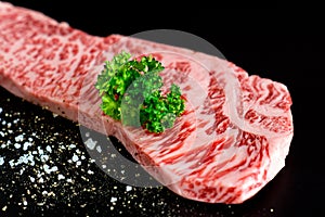 Beef isolated on the black with salt pepper and Parsley close-up