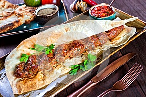 Beef kebab with pita bread, tomato sauce and vegetables on wooden background.