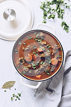 Beef meat stewed with potatoes, carrots and spices in cast iron pot