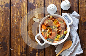 Beef meat and vegetables stew in white bowl on dark wooden table