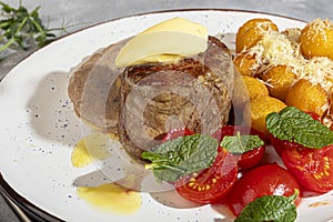 Beef medallion with potato balls and mushroom sauce, topped with a piece of butter