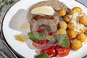 Beef medallion with potato balls and mushroom sauce, topped with a piece of butter