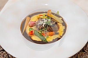 beef medallion on top of yellow sauce with carrots and flowers from the garden at fine dining italian restaurant