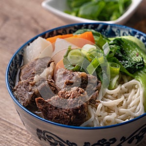 Beef noodle soup. Close up of Taiwanese famous food in a bowl on wooden table