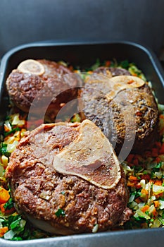 Beef ossobuco meat on tray with crushed vegetables