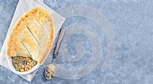 Beef pot pie or deep dish pie in baking dish, crust broken open, horizontal, top view, copy space